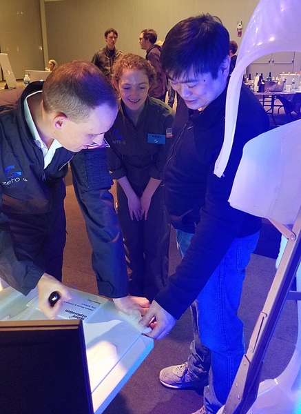 Carson Smuts, Ariel Ekblaw, and Joi Ito examine a project display at the symposium.