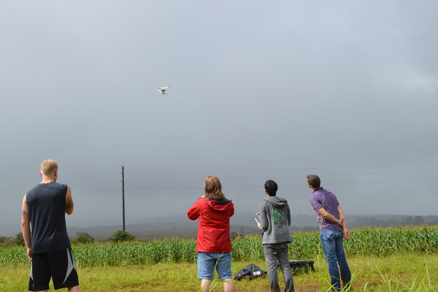 TREX students and Professor Ben Kocar (right) launching their unpiloted aerial vehicle over a local farm to collect data about crop health.