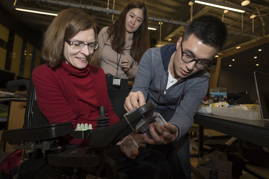 From left to right, co-designer Elizabeth Dean-Clower, Johae Song, a graduate student studying design at Harvard, and Yiran Gao, a graduate student studying engineering management at Northeastern University, collaborate on building a camera system that would allow Dean-Clower to see behind her wheelchair.
