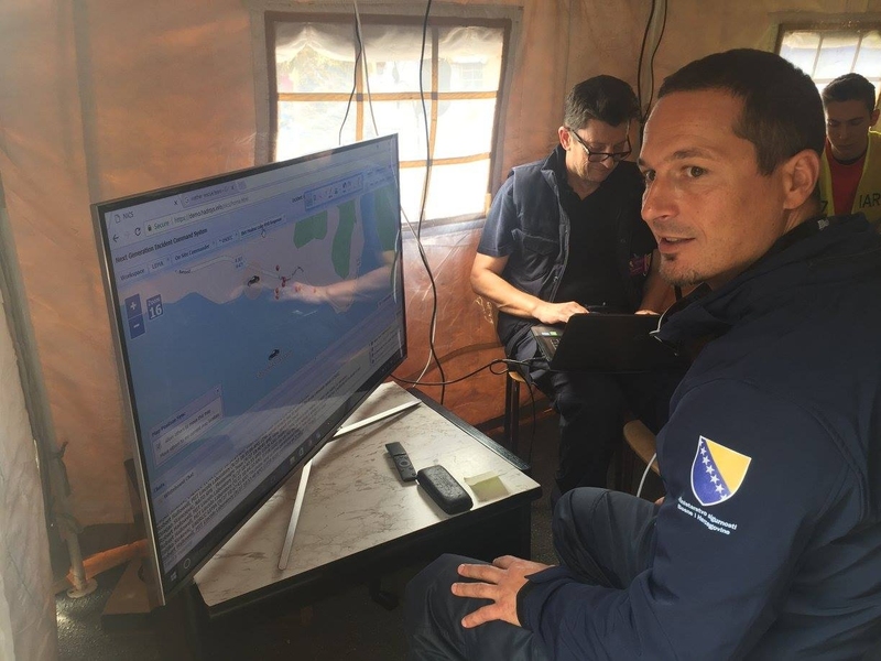 In the NICS command and control tent at the base of operations, Zeljko Sinkovic, who is working with the Laboratory to develop the Southeast Europe version of NICS, inputs information into the system. On the map, a car icon has been placed where responders have confirmed it has crashed, and the red dots represent the locations of responders.