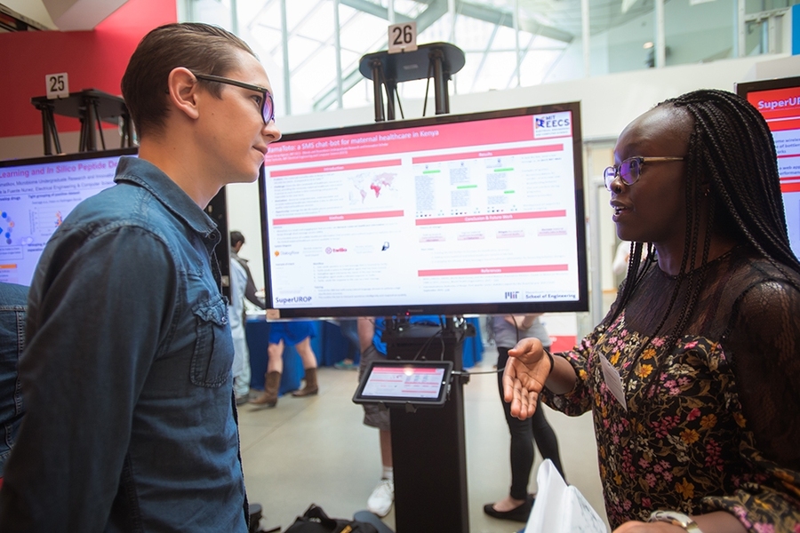 EECS senior Sharon Kipruto (right) describes a telemedicine project that she hopes will reduce infant mortality in Kenya by allowing pregnant women to receive important health information via text messages to their cell phones.  