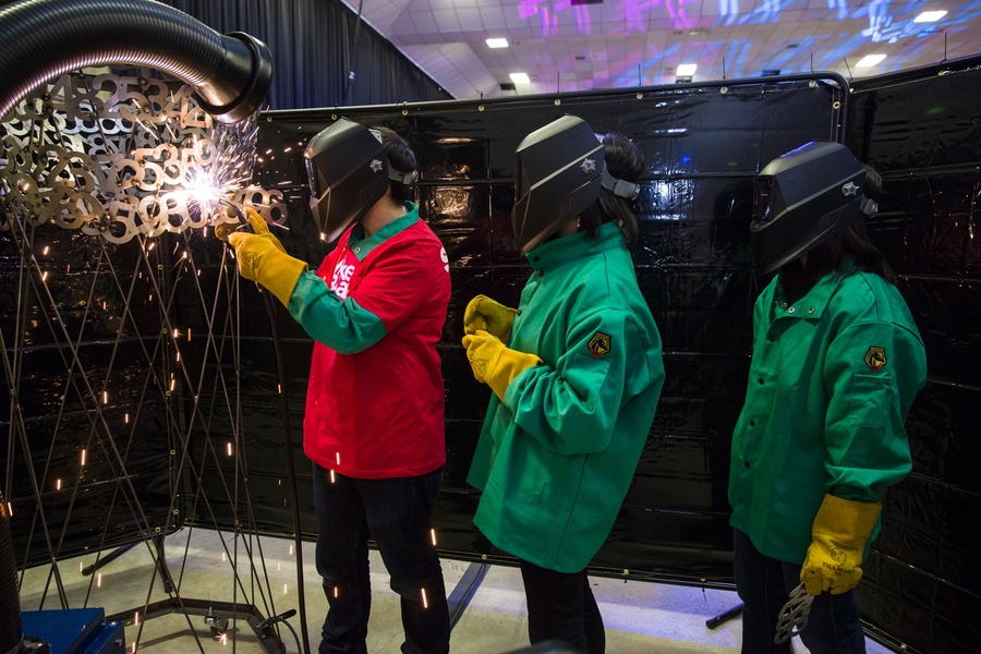 Spot welding steel numerals as part of a collaborative sculpture building at least the first thousand digits of pi at one of the making stations.