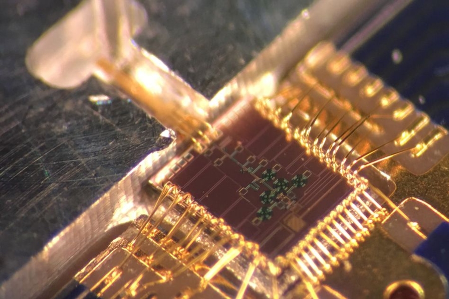 The clock transmitter chip (brown square) wired to a circuit board package. Connected is a metal gas cell (at left), in which a 231.061 GHz signal generated from the chip excites the rotation of carbonyl sulfide molecules. When the molecules reach peak rotation, they form a sharp signal response. That frequency can then be divided down to exactly one second, matching the official time from atomic ...