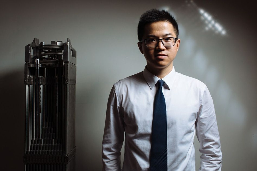 Xingang Zhao standing next to a mockup of a fuel assembly in a pressurized water reactor.