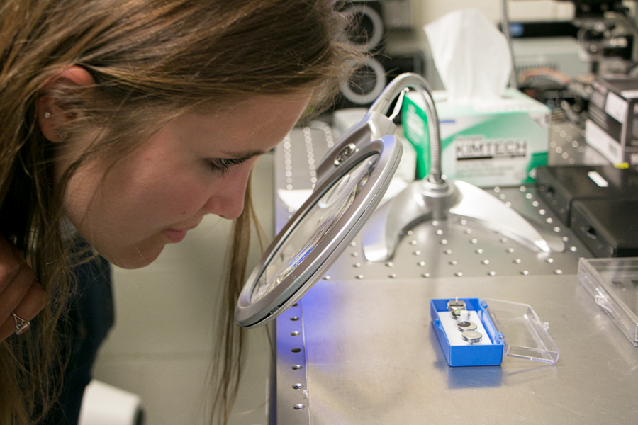 Summer Scholar Sarai Patterson looks through a magnifier at samples of colloidal crystals during a tour of  A. John Hart’s lab.