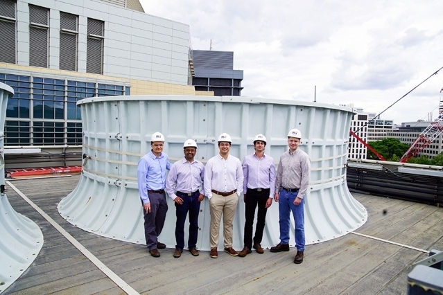On the roof of the Central Utility Plant building, standing in front of one of the cooling towers, are: (left to right) Seth Kinderman, Central Utility Plant engineering manager; Kripa Varanasi, associate professor of mechanical engineering; recent doctoral graduates Karim Khalil and Maher Damak; and Patrick Karalekas, Central Utilities Plant engineer.