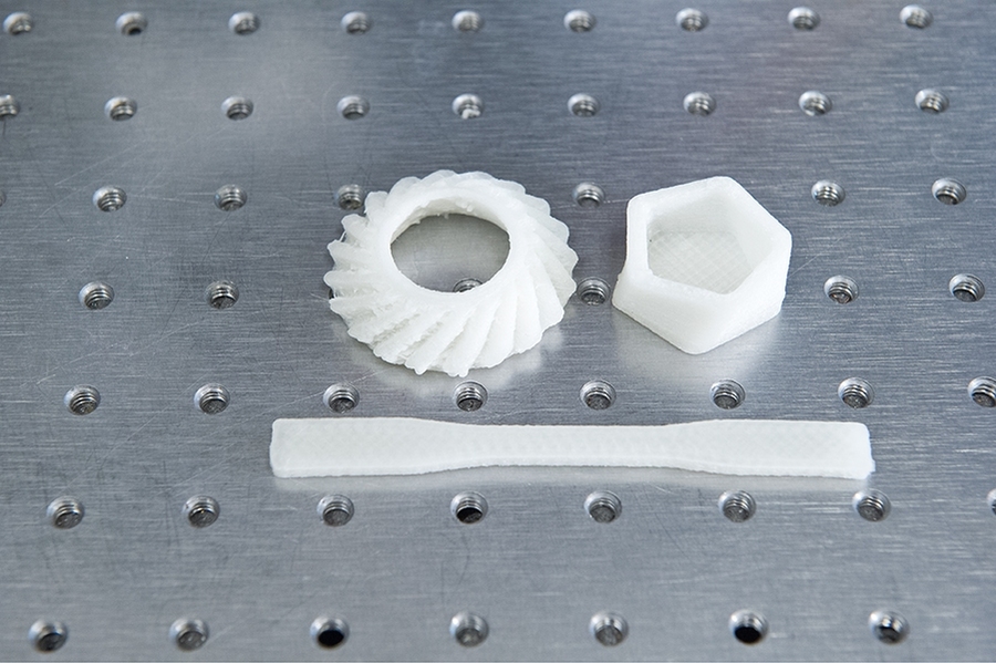 Using the new MIT system and a plastics-based feedstock, the researchers printed a series of test objects. Mechanical testing confirmed that the objects were strong and robust, and microscopic examination showed that the deposited layers were highly uniform. Printing the helical bevel gear (top left) took longest at 10 minutes — a reflection of its complex shape. The dog-bone-shaped object in th...