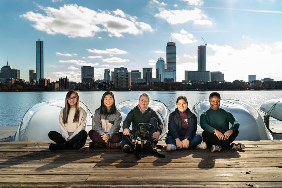 MIT employee Pauline Dowell (center) and her seeing eye dog, Dora, hang out near the Charles River with MIT students from Team Pauline: (l-r) Sandy Yang, Tiffany Xi, Rebecca Agustin, and Temitope Olabinjo.