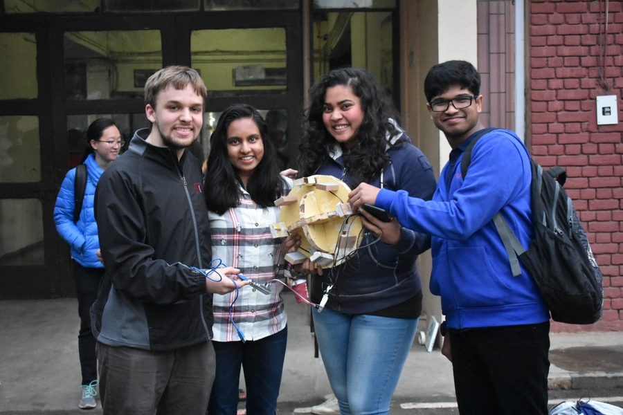 Mark Vrablic '19 (سمت چپ) و Agni Kumar '20 (نفر دوم از چپ) با دانشجويان IIT دهلي كار مي كنند تا يك نمونه اوليه كاربردي از يك تخته تعادل ايجاد كنند كه مي تواند در مورد مسائل تعادلي بازخورد ارائه دهد.