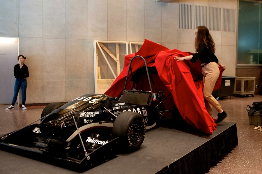 Serena Grown-Haeberli lifts up the tarp to display the MIT Motorsports 2019 model.