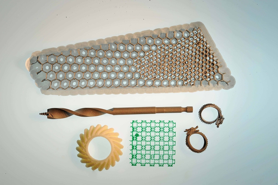 3-D-printed objects related to Professor John Hart’s research including: a scale model of an optimized airplane wing core (top); a metal drill bit and two rings (center and right) produced by Desktop Metal, a company Hart co-founded in 2015; a plastic gear (bottom left), printed on a high-speed machine invented by Hart’s lab that is 10 times faster than commercial counterparts; and a flexible ...