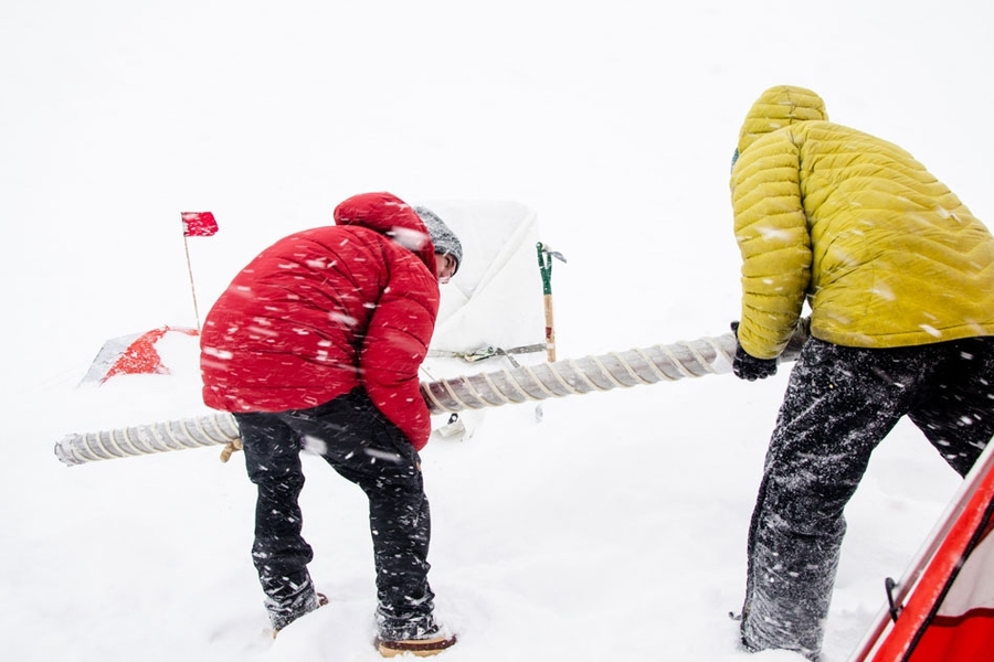Retrieving an ice core section from the drill barrel during a west Greenland snowstorm, west Greenland Ice Sheet.