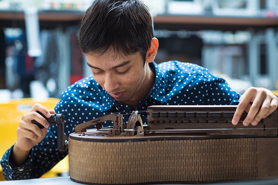 Shahir Rahman demonstrates his 6:08 team’s creation, Hurdy-Gurdy Hero. The project involves using a custom-built plywood version of a medieval instrument to save favorite songs to a database that processes the audio for use in a game.