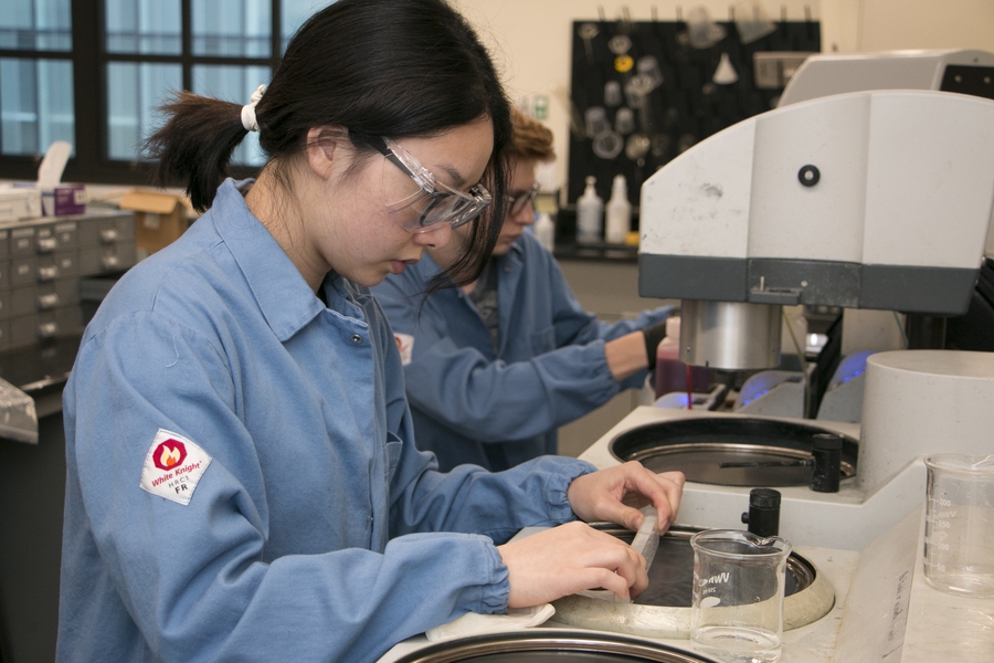 Bunker Hill Community College student Minhua Mei grinds a block of PMMA to expose the electrodes on top in the lab of associate professor of materials science and engineering Polina Anikeeva. PMMA is a polymer that is sensitive to electron beams. After grinding exposes the electrodes, the approximately 10-inch long PMMA block will be drawn in a fiber tower to about 100 times its length, or 82 feet...