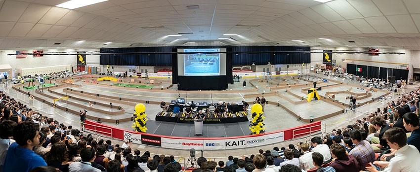 Robert Shin speaks to attendees of this year's Beaver Works Summer Institute final event with the RACECAR obstacle course in the background.