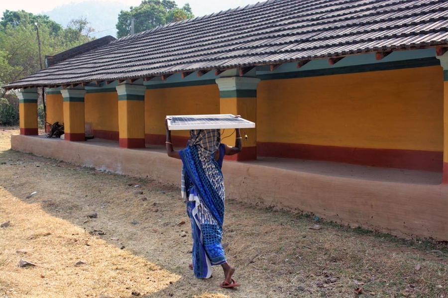 A woman carrying a Khethworks solar panel. The efficiency of Khethworks' groundwater pump enables it to be powered by smaller panels, making the system portable.