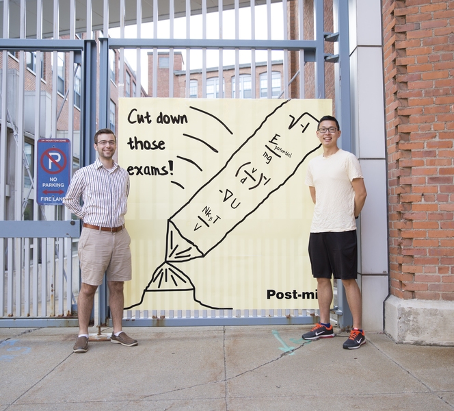 Nick Demas PhD '19 (left) and Jerry Wang PhD '19 stand outside Edgerton House with a larger-than-life note of encouragement.