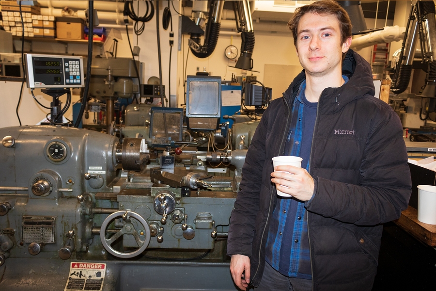 Graduate student Austin Brown stands in front of the Monarch EE hand-operated lathe.