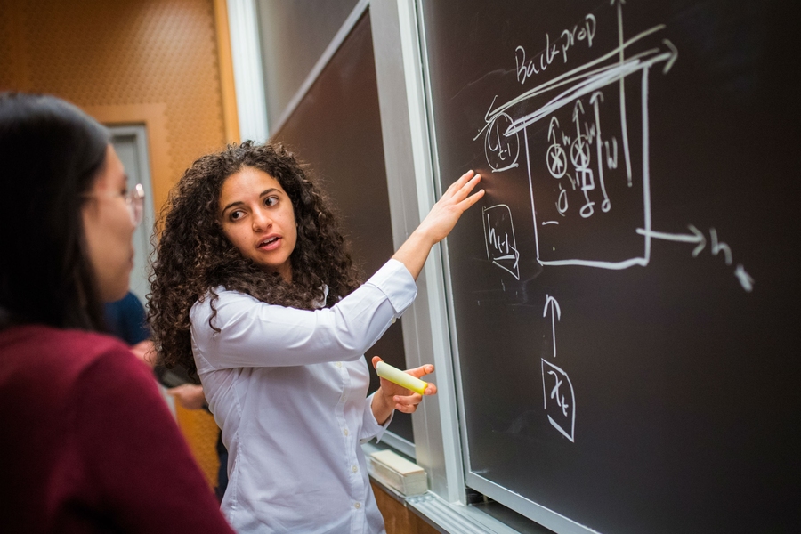 The instructors and a cadre of teaching students are on hand to help with questions after class. Here, Ava Soleimany explains back propagation.