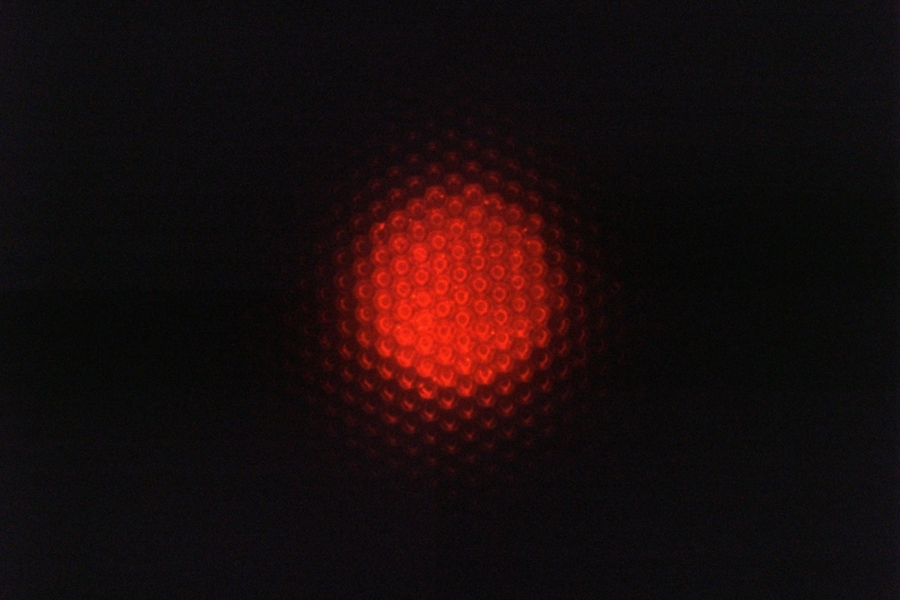 This optical micrograph of the inside of a luminescent substrate shows the red fluorescent emission from the quantum dot layer on top of the micropatterned bottom reflector. 