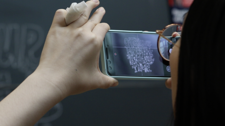 Charleen Wang takes an image of the chalk art to post on the Chalk of the Day instagram.