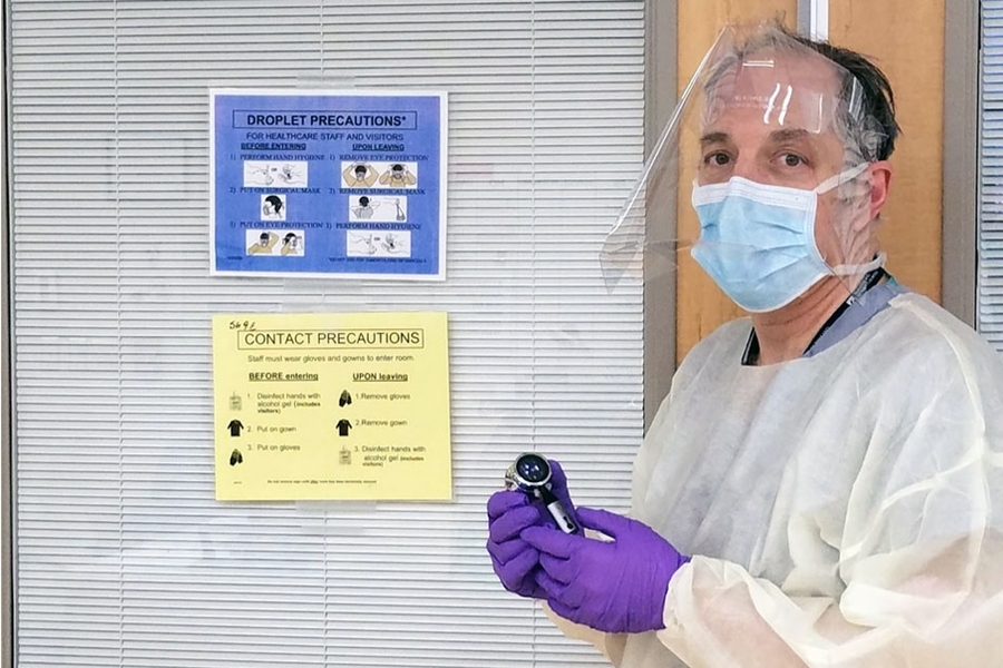 Elazer Edelman, the Edward J. Poitras Professor in Medical Engineering and Science at MIT, wears a face shield developed through a collaborative effort involving groups across MIT, while holding an electronic, Bluetooth-enabled stethoscope. In this photo, Edelman is wearing the shield in the snapped up position health care workers also have the option to use.