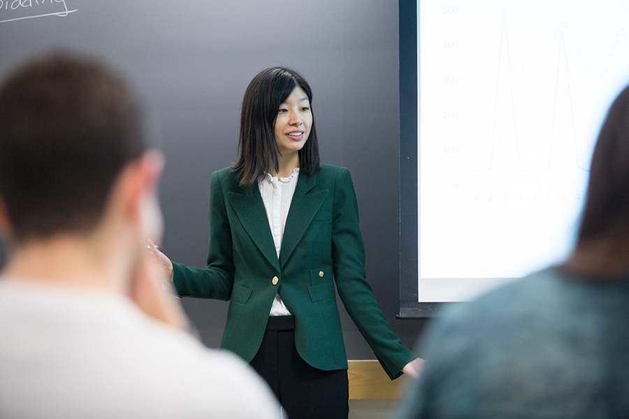 Jing Li, an assistant professor of applied economics, engages with her students during the Electricity Strategy Game debrief.