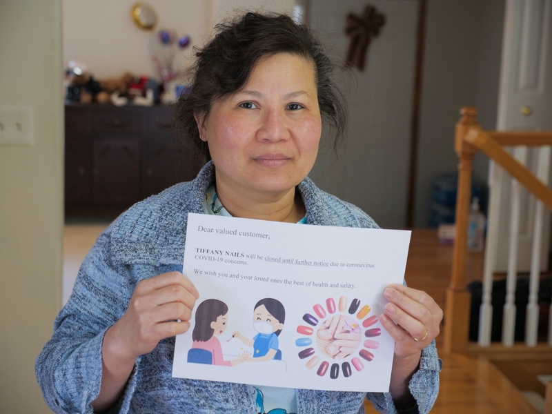 Truong's mother holds a sign to note that her business is closed until further notice.