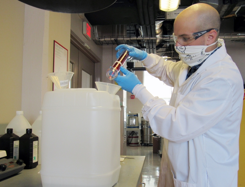 Alec Casavant, assistant officer in the Environmental Management Program within EHS, adds ingredients while making a batch of hand sanitizer.