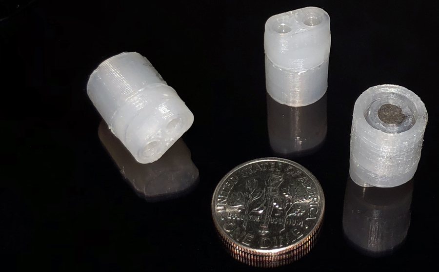 Three 3D-printed pumps next to a dime for size comparison