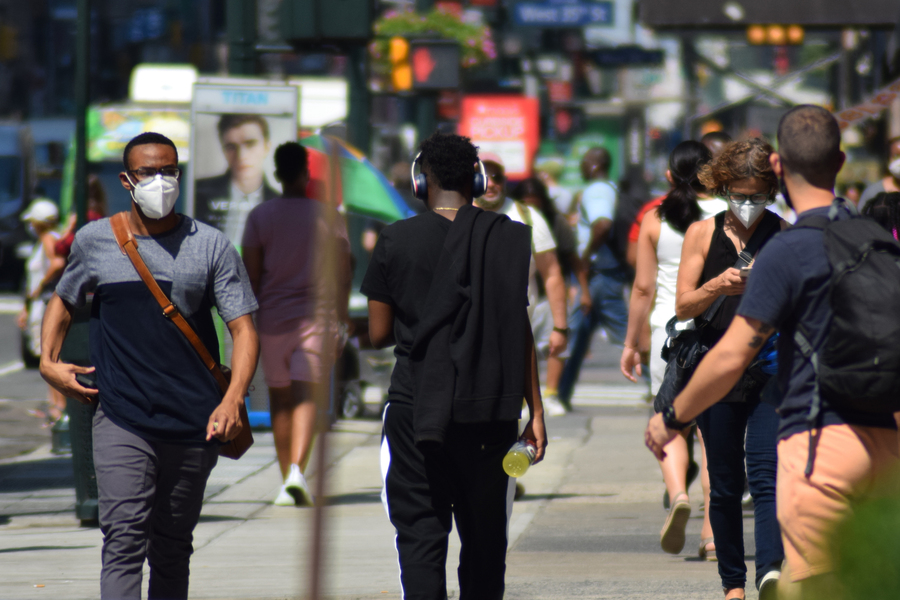 Photo of people wearing masks walking down a busy street