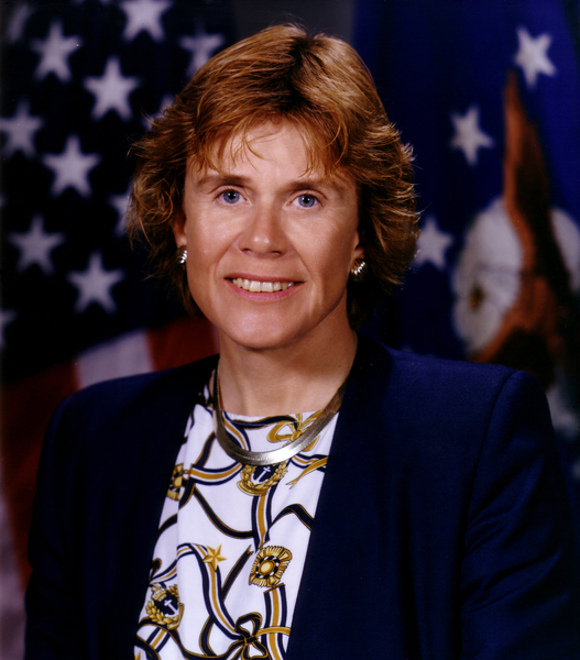 Sheila Widnall smiling in front of a United States flag