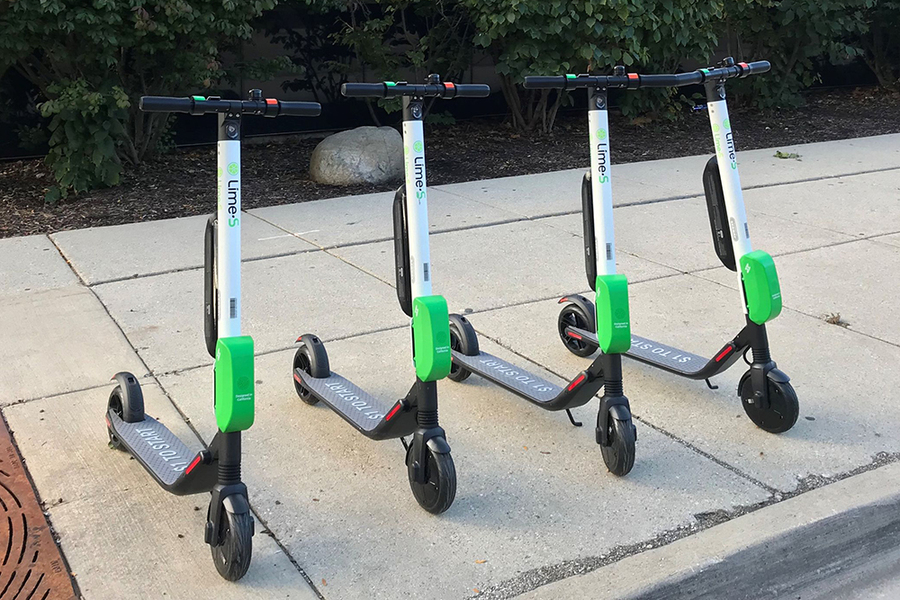 Four scooters stand ready for bike-share rental on a sidewalk