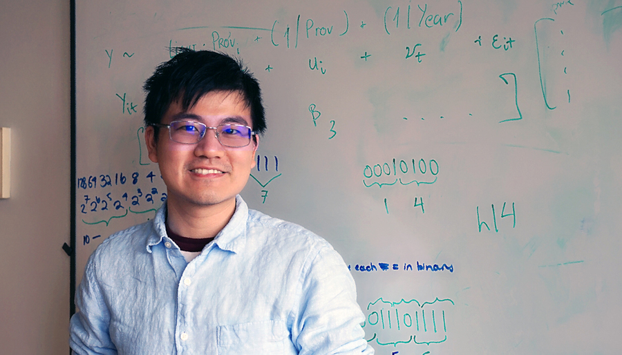 Photo of Sean Liu in front of work on a white board