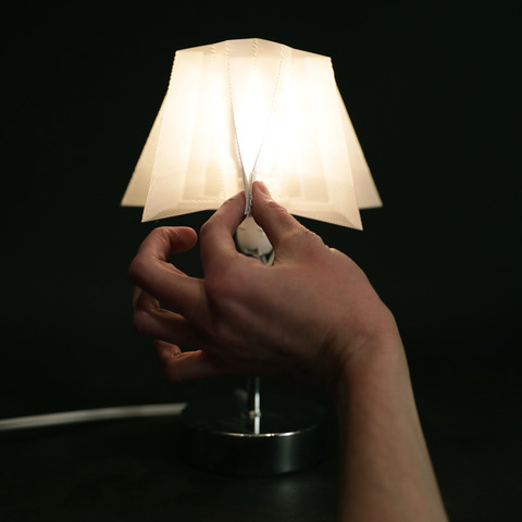 Photo of a hand holding up a 3D-printed lamp