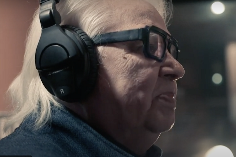 A profile portrait of Ojibwe Elder Duke Redbird, wearing headphones