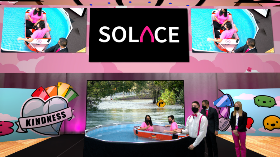 Photo of a group of students presenting on stage with a small pool. Two students sit on a life raft in the pool