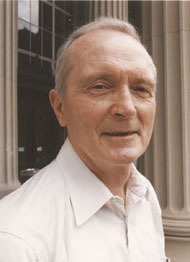 Photo of Emeritus Professor Peter Eagleson standing in front of columns at MIT