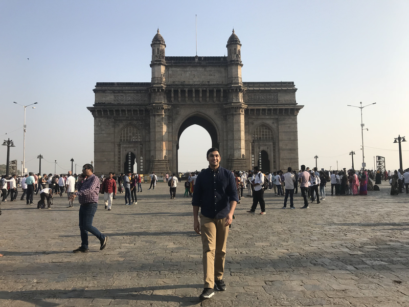 Photo of a student standing in front of architecture in India