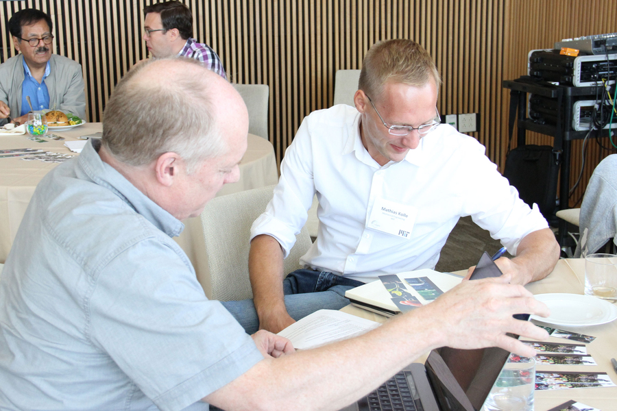 Photo of two men in conversation around a table taking notes