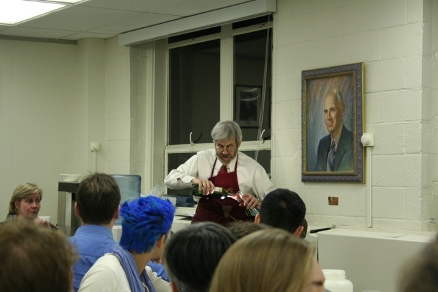 Photo of Linn Hobbs decanting wine in a classroom while half a dozen participants look on