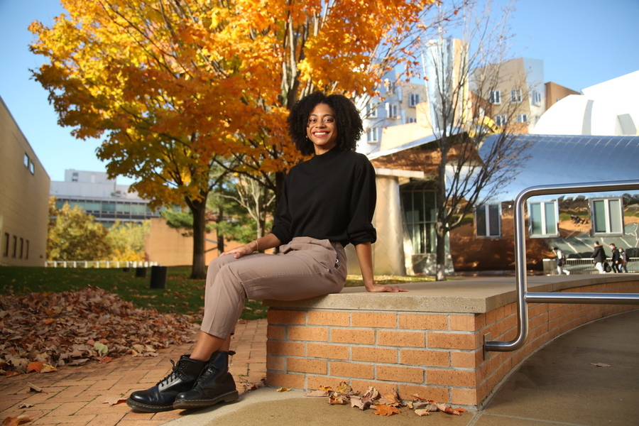 Photo of Orisa Coombs posing in front of the Stata Center on a nice fall day