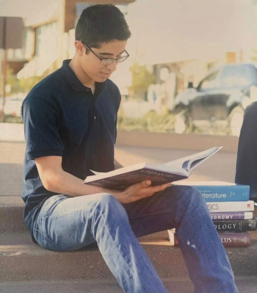Photo of Sergio Dominguez sitting on some steps and reading a book