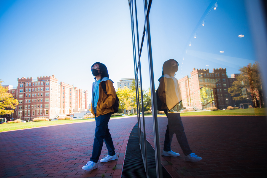Photo of a student with a mask, walking on campus