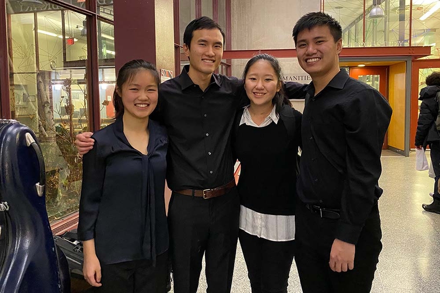Photo of musicians Jiaxing Liu, Alex Wang, Jeana Choi, and Jeff Chow standing with their arms around one another and smiling