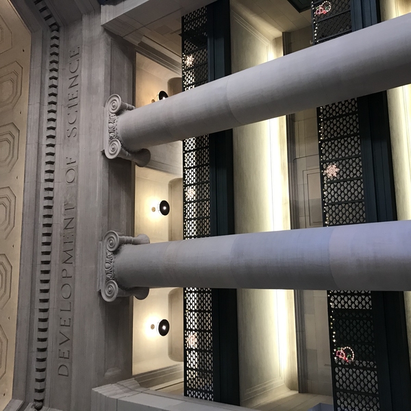 Photo of columns and balconies in MIT Lobby 7 with the etched words "development of science" running around the ceiling