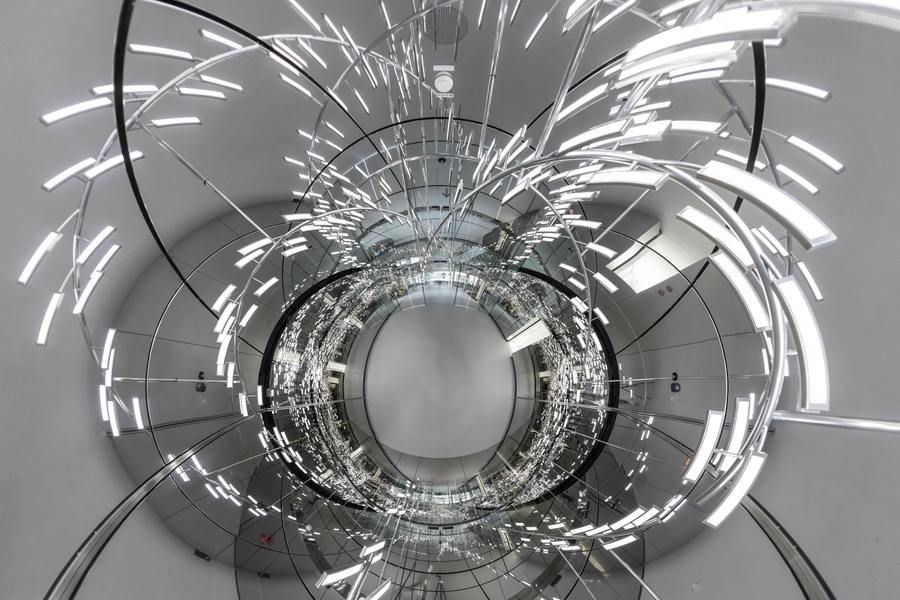 Photo collage: A photo of ceiling lights maniuplated into what appears to be a metallic sculpture. A central sphere is surrounded by linear elements that might represent magnetic field lines