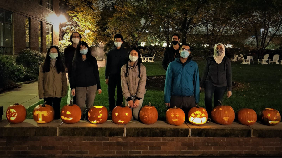 Eight students in masks pictured in front of orange carved pumpkins
