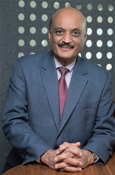 Portrait photo of Bhaskar Pant wearing a suit and tie, smiling, with his hands folded