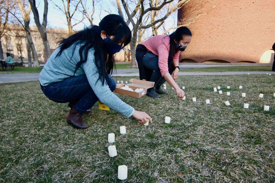 Photo of Lily Cheng Zedler and Chloe Lim setting up candles on Kresge Oval.